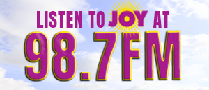 Promotional banner for radio station 98.7 FM with the word JOY and a sun graphic (Listen to JOY)